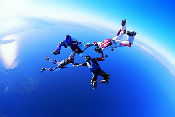 Vol de quatre parachutistes dans le ciel bleu