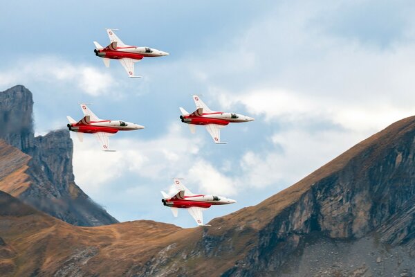 4 red and white planes in the mountains