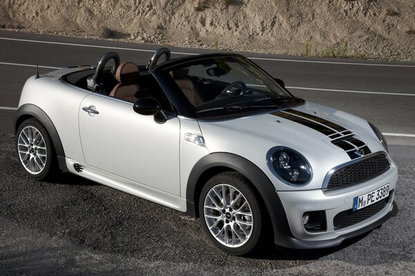 White mini Cooper without a top on a gray road