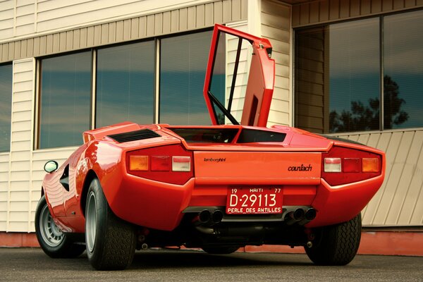 Красный lamborghini, countach lp400 1974 года на фоне здания