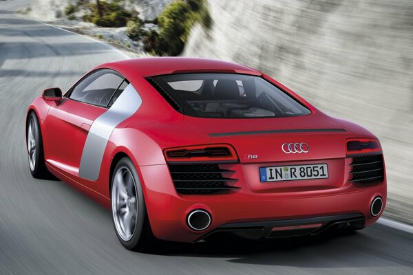 A red Audi car rushes along a dirt road