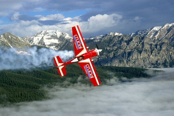 Pequeño avión rojo en el fondo de las montañas cubiertas de nieve