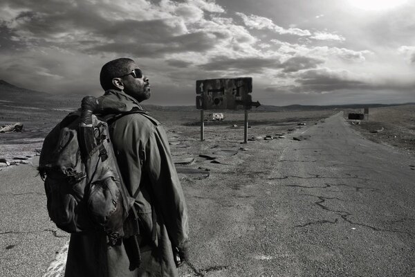 A dark-skinned man looks at the road