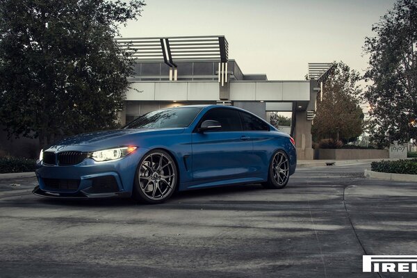 Blue bmw f 32 on pirelli tires on the background of the house