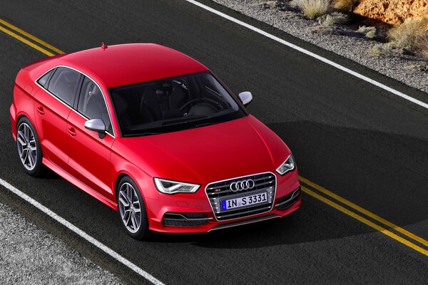 Red Audi rides on asphalt