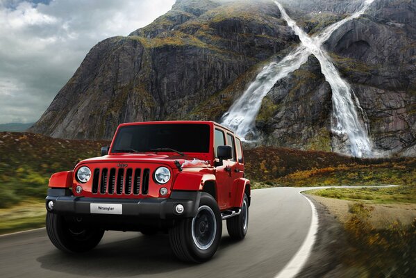 Coche Wrangler X en una carretera de montaña en medio de una cascada