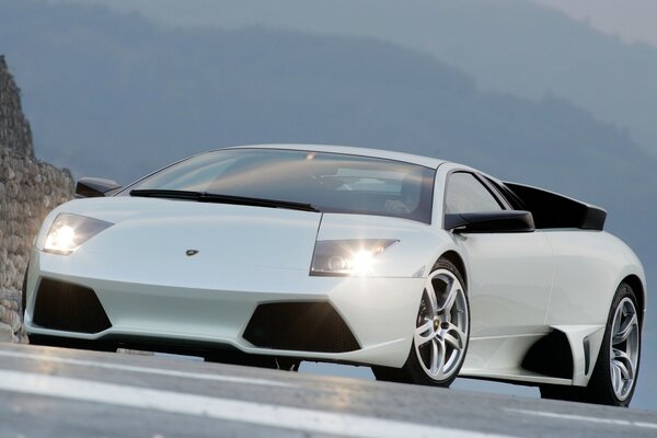 Lamborghini blanc sur la route avec les phares allumés