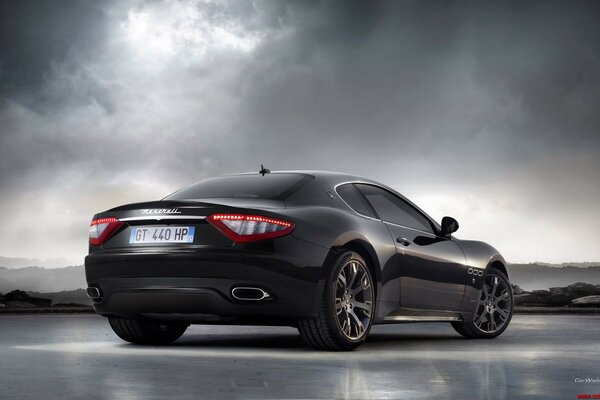 Stylish black car on a cloudy sky background