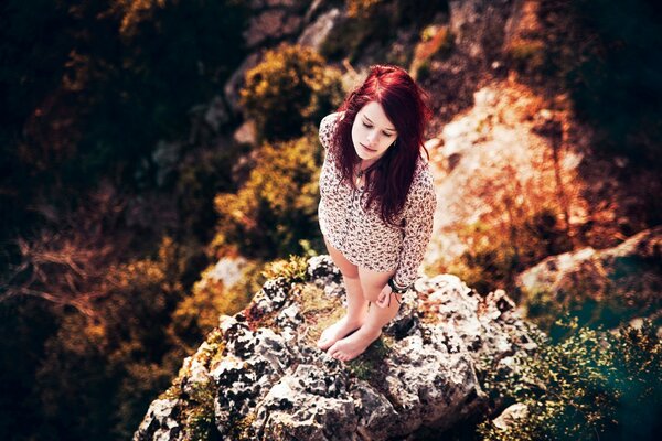 Rousse fille debout sur la pierre près de la falaise