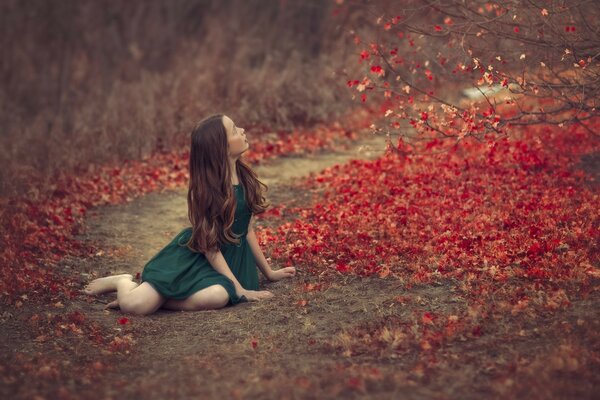 Fille en robe verte est assis dans le feuillage