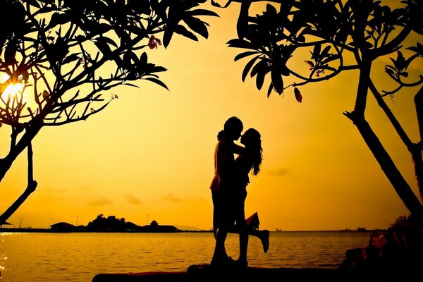 A guy and a girl hug against the background of the sunset