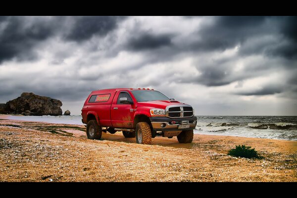 A red large car is parked near a pond