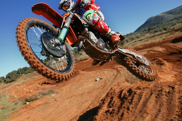 View from the front of the KTM motorcycle during the performance of the trick on a clear sky background