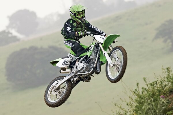 Motorcyclist on a motorcycle in flight over a meadow