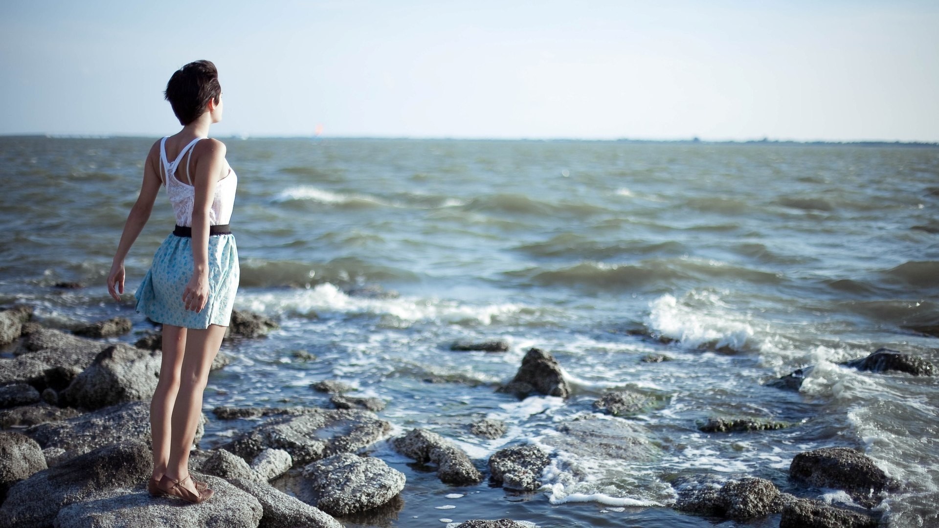 a woman girl brunette stone grey sea water ocean