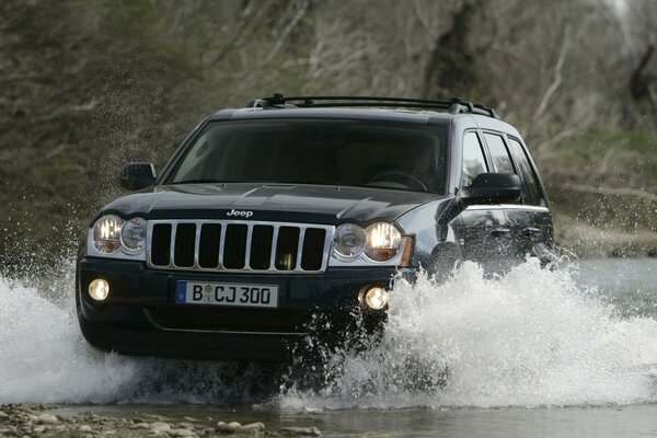 Jeep confidently rides along the river in the mountains 