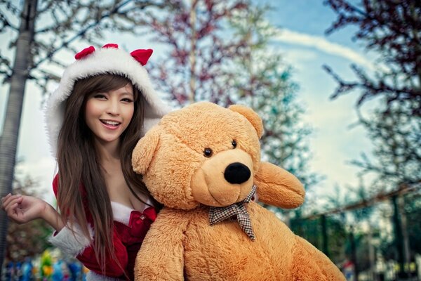 Fille en costume de Noël avec un gros ours en peluche