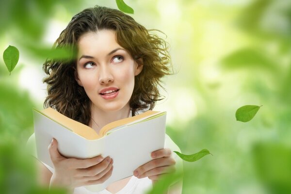 Una chica con un libro bajo las hojas que caen