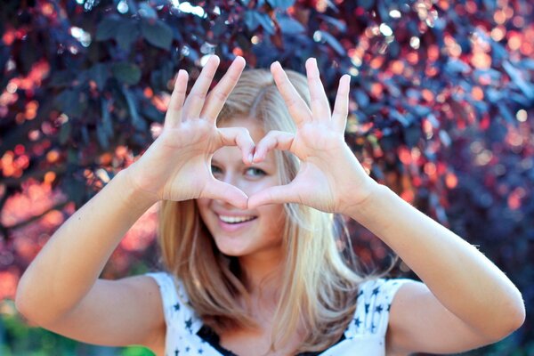 Fille blonde montre le cœur avec ses mains