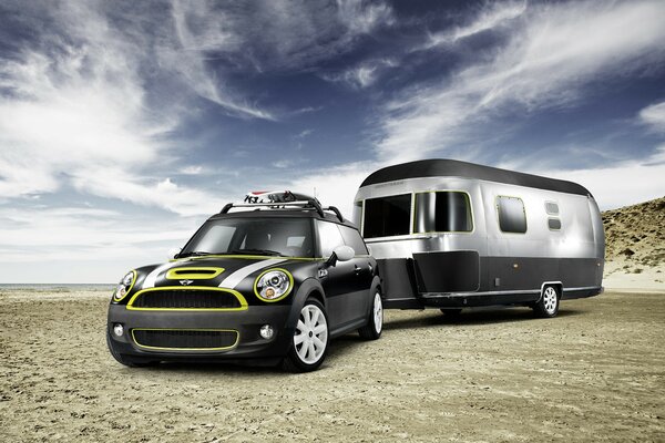 A car with a trailer travels in the desert