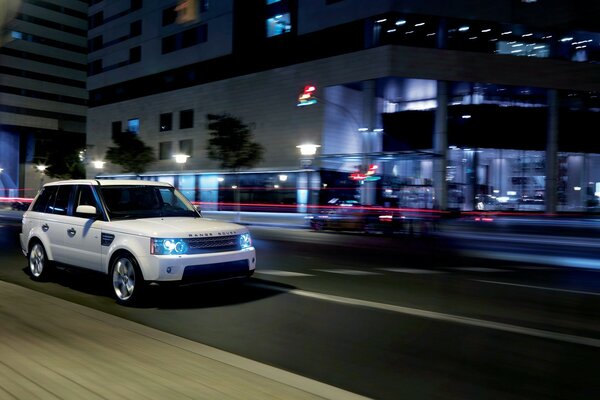 Range rover por la noche en la calle de la ciudad