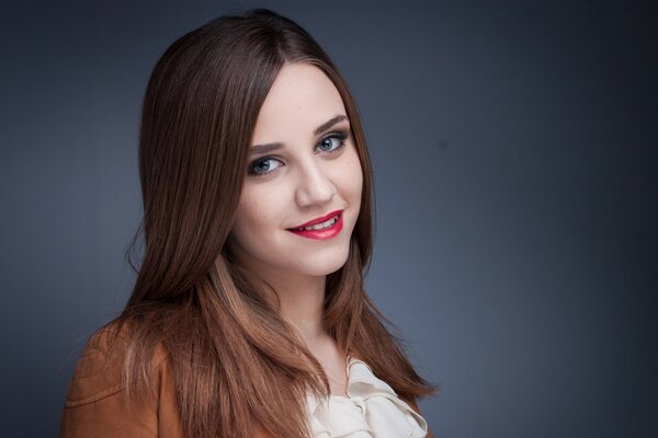 A cute brown-haired woman with red lipstick on her lips is smiling