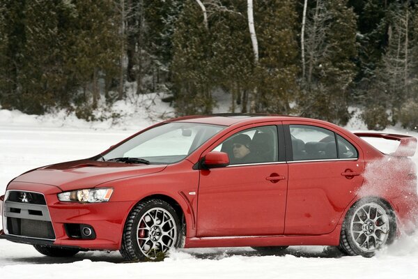 Red mucibisi lancer enters the turn on the winter highway