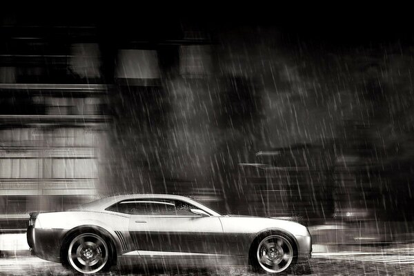 Un chevrolet camaro pintado viaja bajo la lluvia