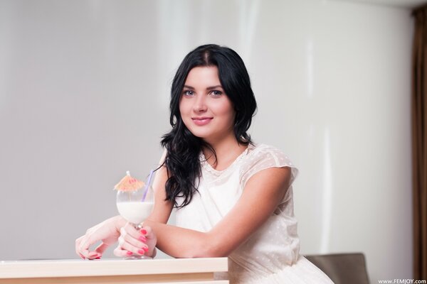 A brunette with long hair is sitting at a cocktail table