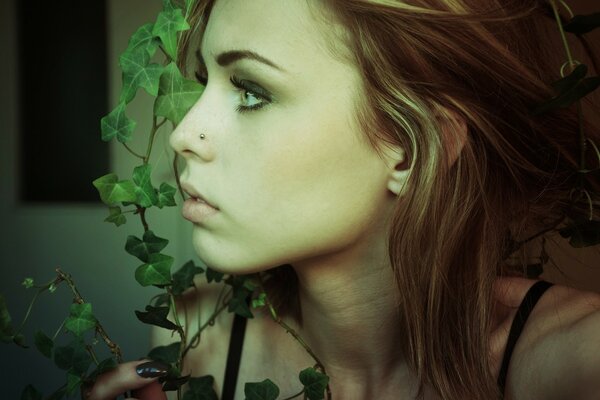 A girl with brown hair is wrapped around a rich green vine