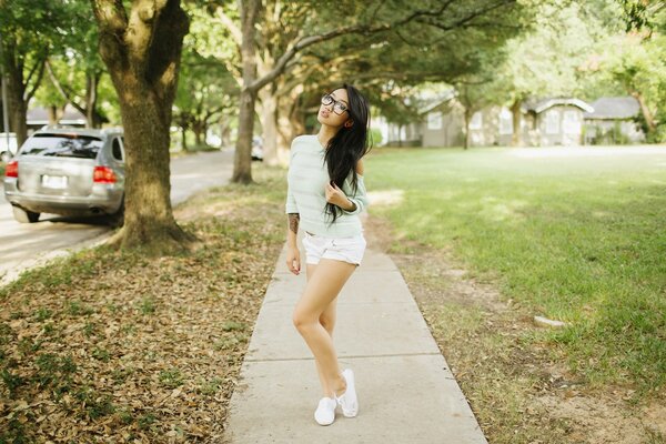 Asiatische Frau mit Brille steht im park