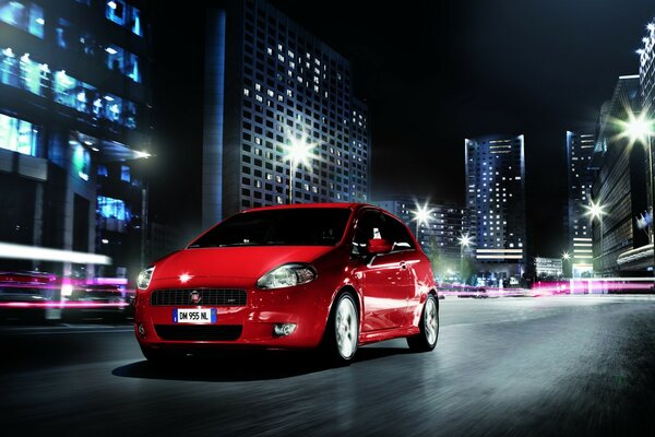 Coche rojo en movimiento por la ciudad de la noche