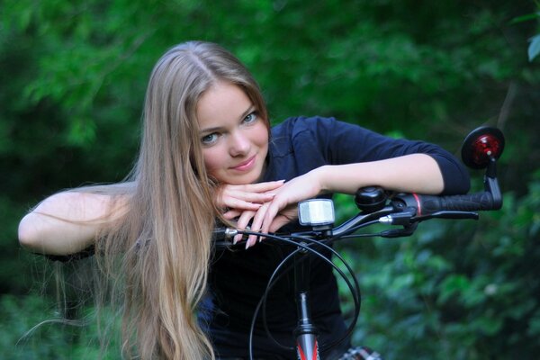 Chica rubia se sienta en una bicicleta