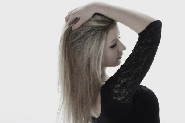 A girl in a black dress straightens her hair