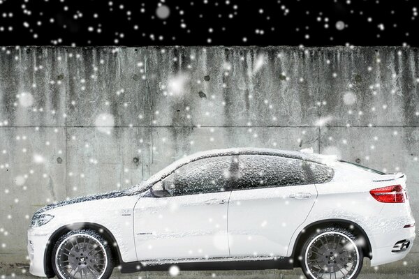 BMW X6 blanco bajo la nieve que cae