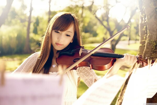 Asian woman plays the violin according to the notes