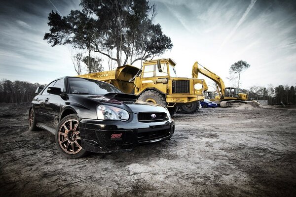 A black sparkling car and a yellow excavator