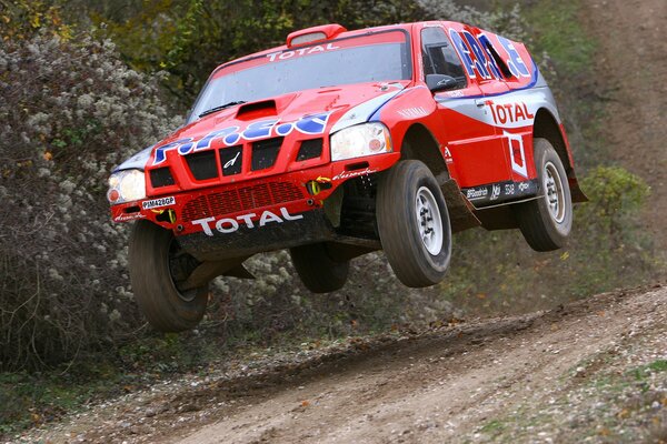 Un coche rojo conduce por un camino de tierra