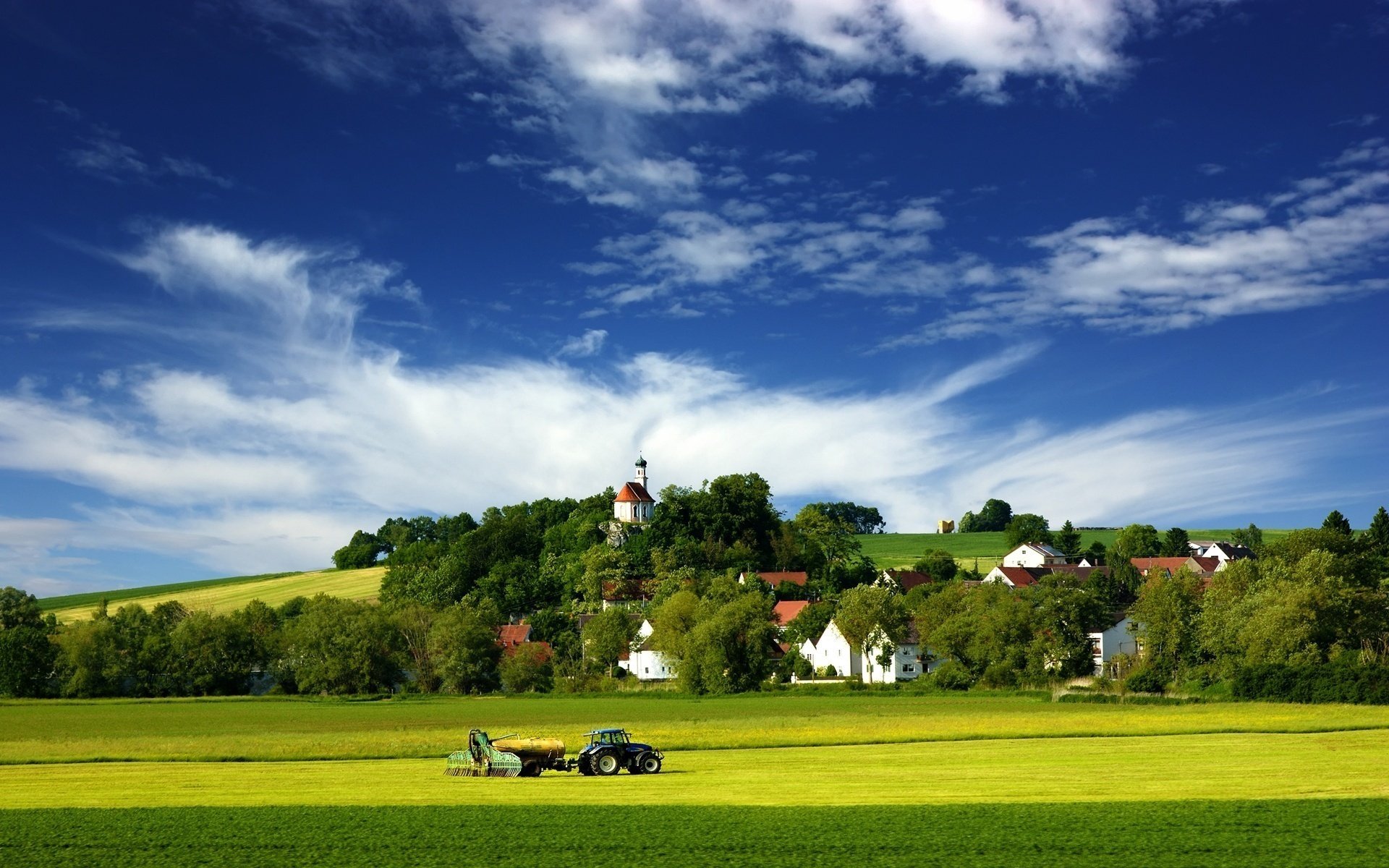 foin été tracteur champ prairie verdure nature ciel nuages paysage village maisons arbres colline