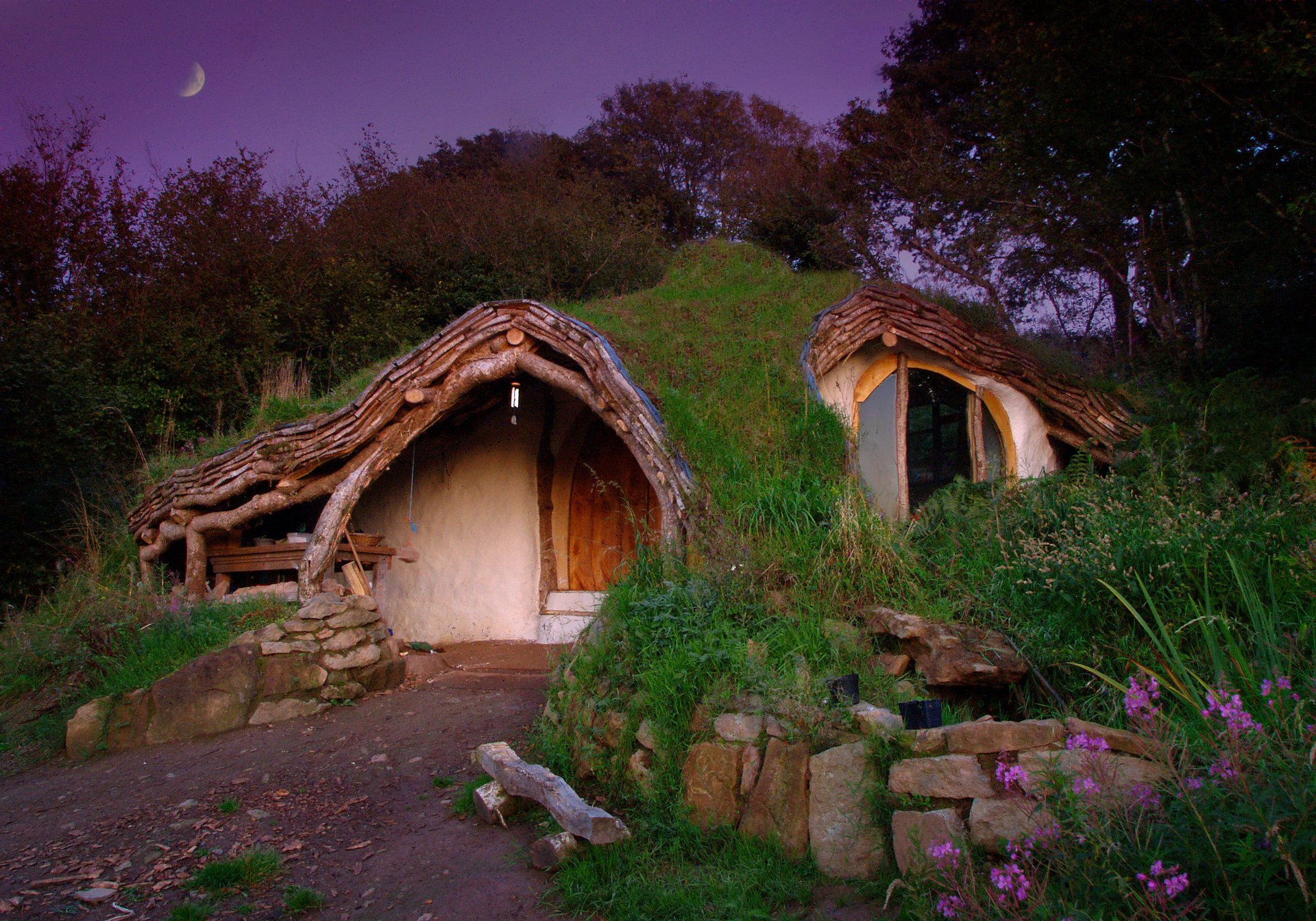 bilbo & frodo bag-end hobbiton panchina fiori panchina fatta in casa il signore degli anelli la shire john ronald reuel tolkien paesaggio natura estate erba verde pietre sera cielo lilla luna casetta alberi boschetti cespugli pietra selvatica