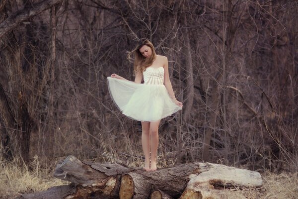 Chica en vestido blanco en un tronco