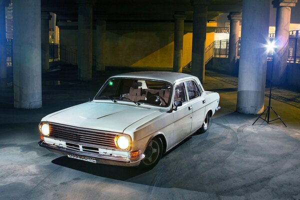 El coche Volga 24-10 blanco en el Aparcamiento en el edificio