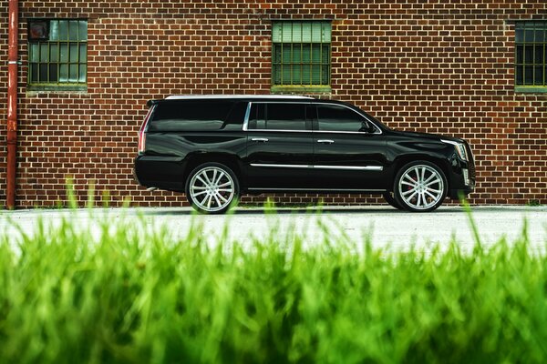 An SUV standing on the road near a brick building