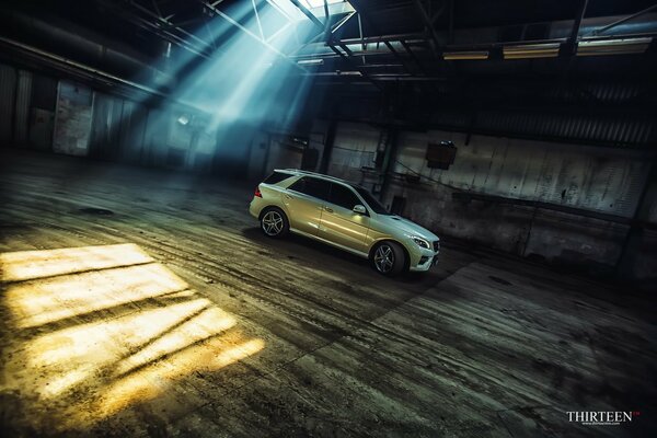 Mercedes blanco en la pared más alejada de un gran hangar semi oscuro