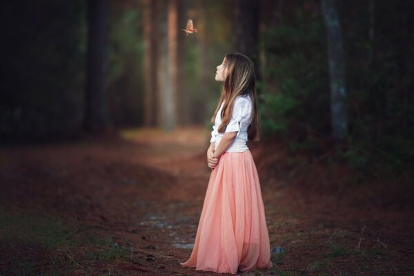 Fille en jupe rose dans la forêt avec un oiseau