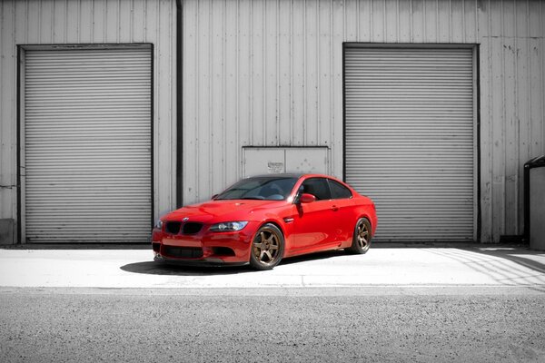 Un automóvil BMW de color rojo en el fondo de un edificio con dos puertas y un tablero