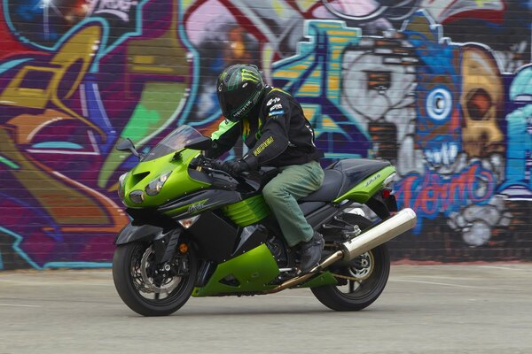 A man on a motorbike on the background of graffiti on the wall