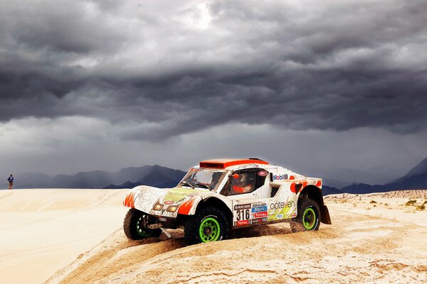 The car is driving through the desert under thunderclouds