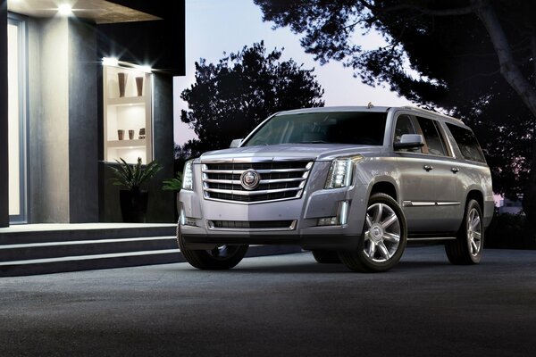 A silver-plated SUV is parked next to the house