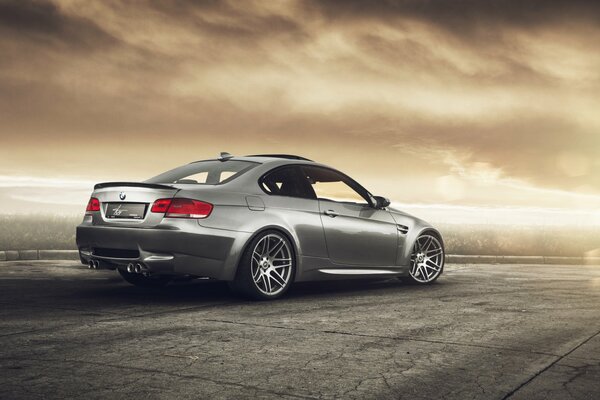 Voiture BMW argent sur la route grise sous le ciel brun